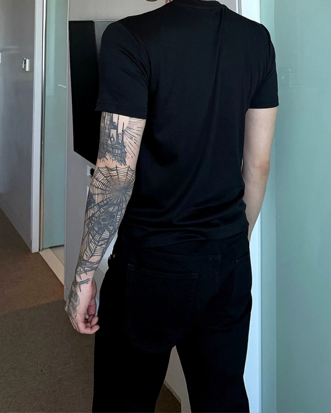 黒い半袖Tシャツ。後ろ姿で、シンプルなクルーネック、タイトなシルエット。
