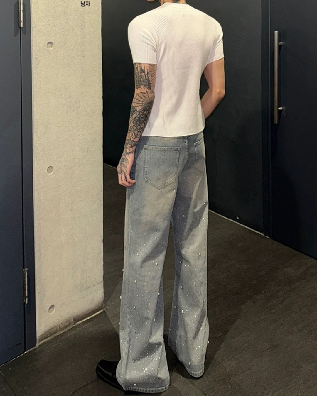 白の半袖リブニットカットソー。タイト寸法で身体に沿うシルエット。グレーデニムパンツに合わせた着用画像で後ろ姿から撮影。