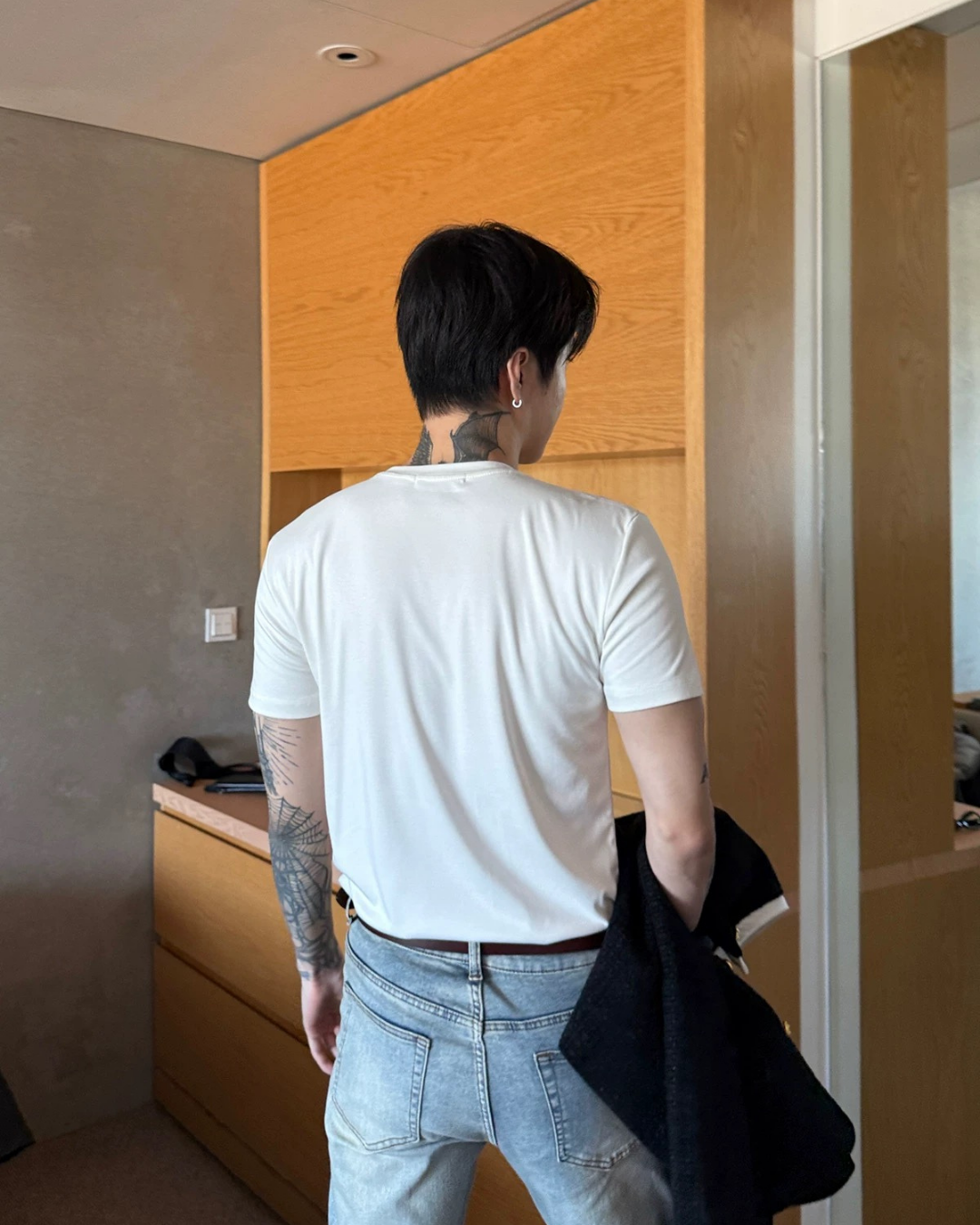 白色の半袖Tシャツを着た後ろ姿。ボディにドレープが自然に落ち、ライトブルーのデニムとスタイリングされた着用例