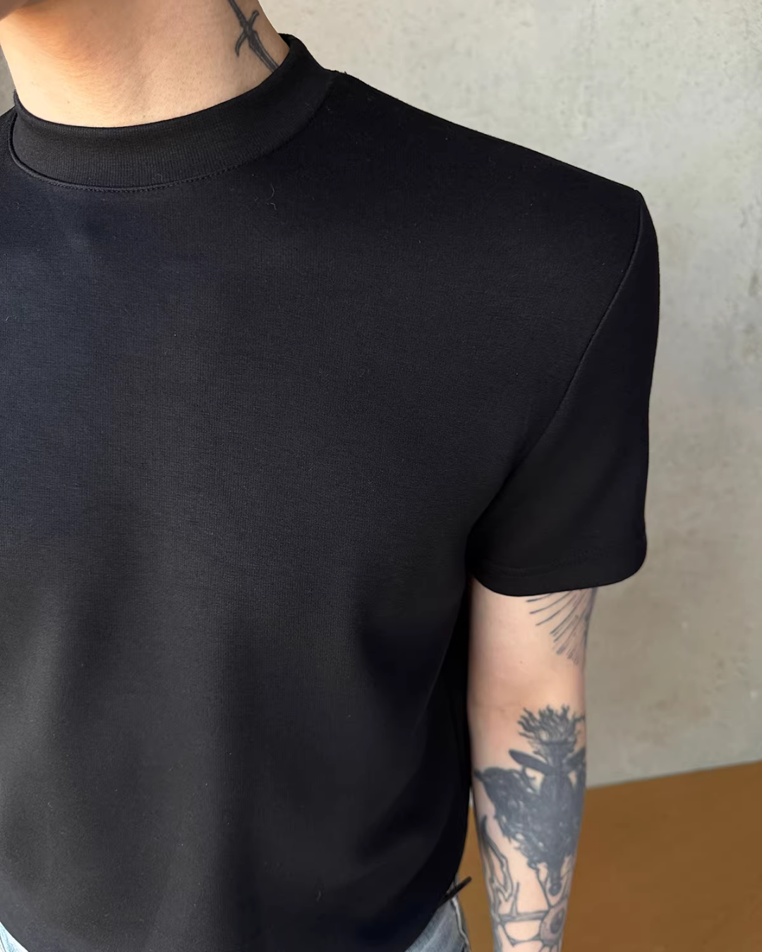黒のクルーネックTシャツ。半袖でリブ編みの襟、シンプルなストレートシルエット。