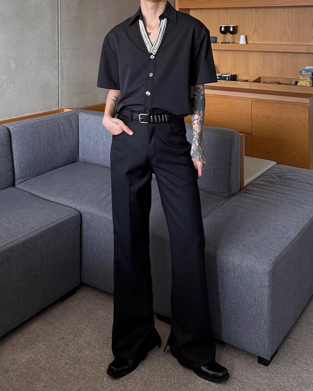 黒のストレートレッグパンツ。ハイウエスト、スリット入りベルト付き。幅広のまっすぐなシルエット。