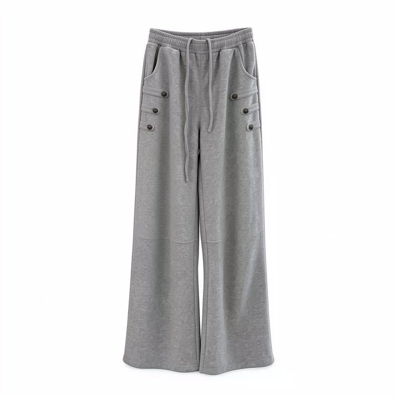 メンズのグレーのワイドスウェットパンツ単体の正面。ウエストはゴムとひも、腰の両脇にボタン付きの飾りが3段ずつ付く。