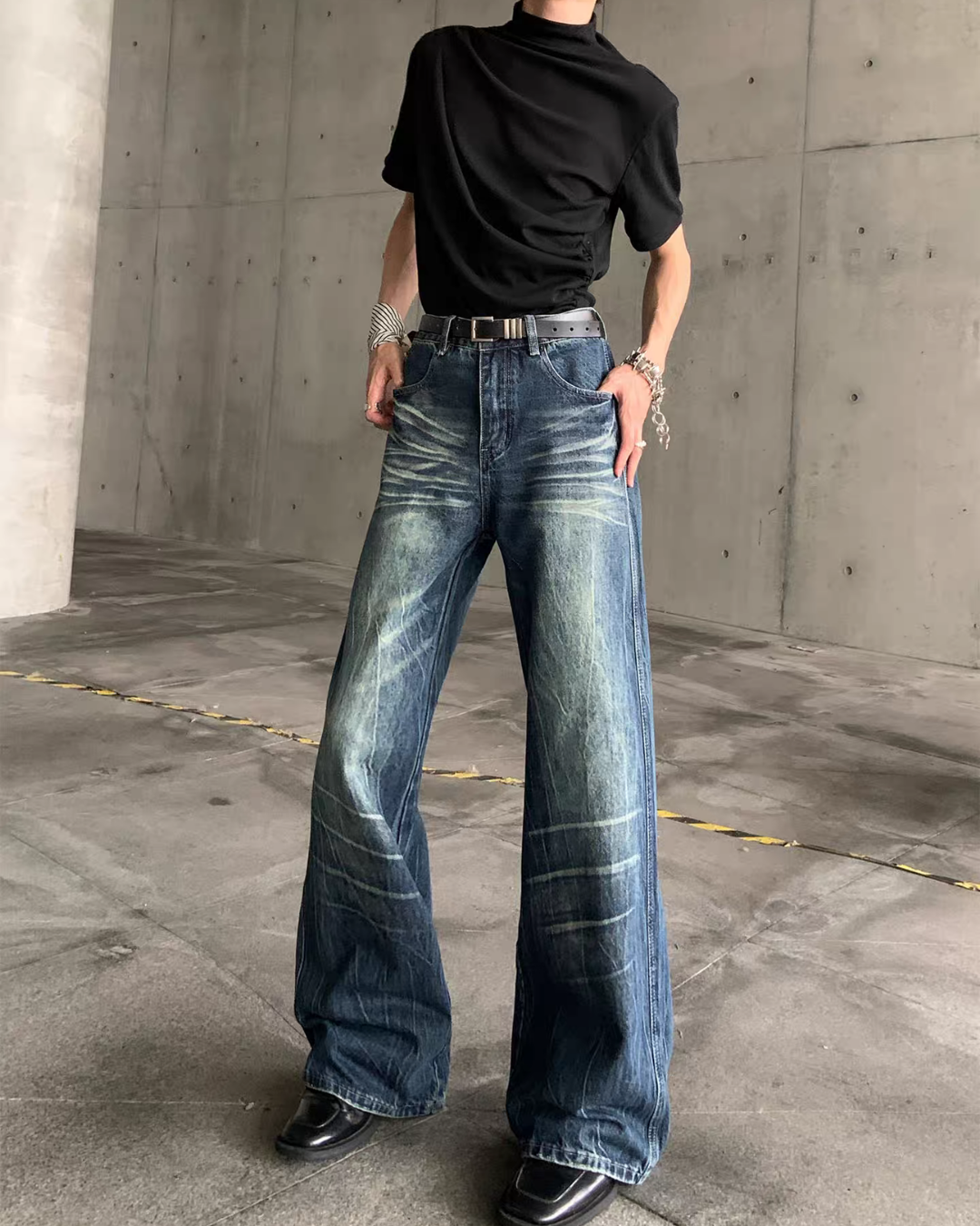 メンズの濃いインディゴのワイドデニムパンツ。両手をポケットに入れた着用で、ゆとりのある太さと、腿の白いヒゲ加工が見える