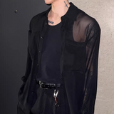 黒いシースルーシャツ。襟付き、前ボタン留め、長袖。透け感のある素材で、肩から胸部にかけて透き通っている。