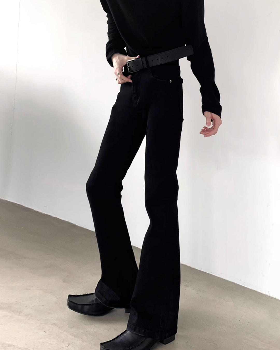 メンズの黒デニムのハイウエストフレアパンツ。黒ベルト付き、裾に向けて広がるシルエット。