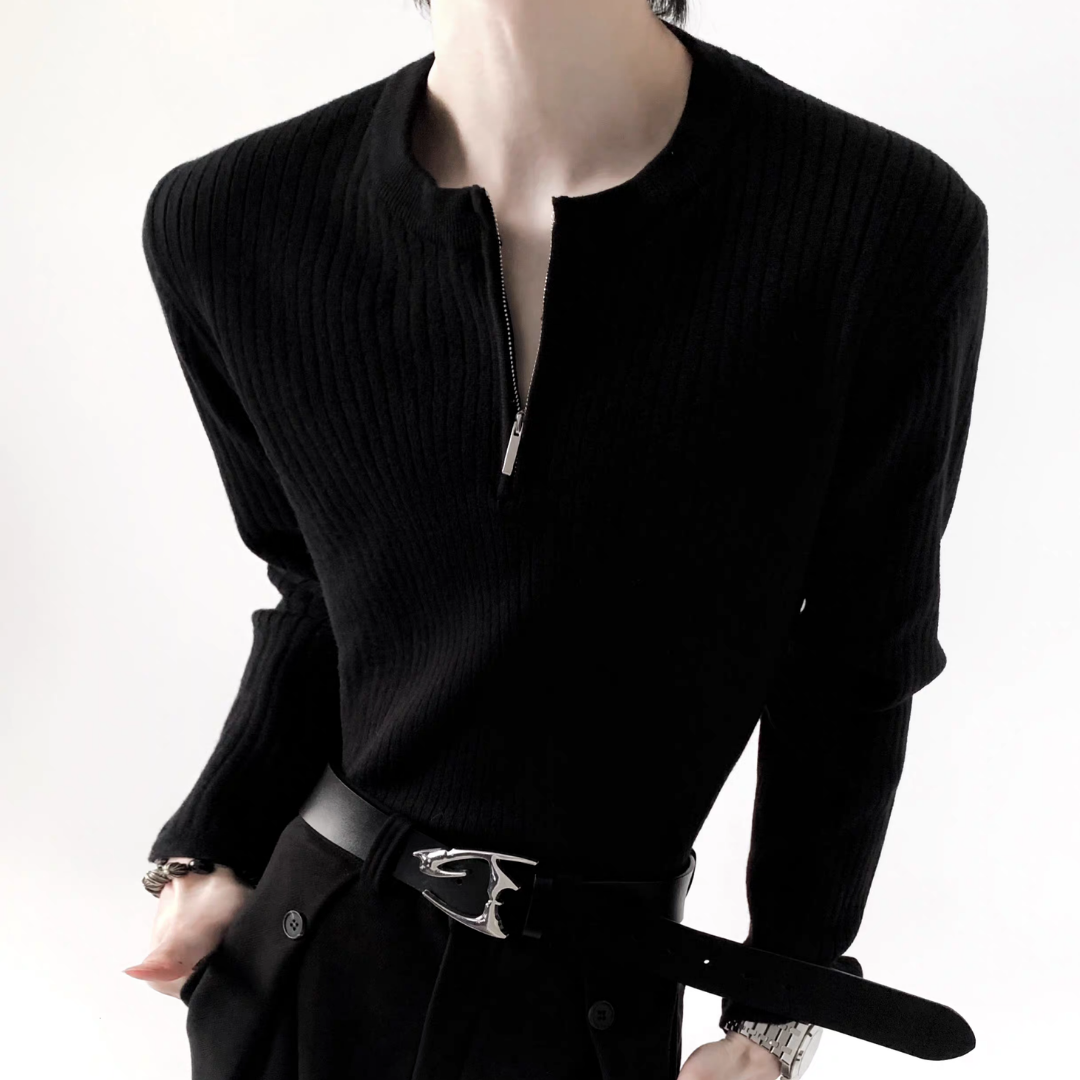 黒のリブニット。ハイネック、前身頃にシルバージップ、長袖。モデルが黒レザーベルト着用。