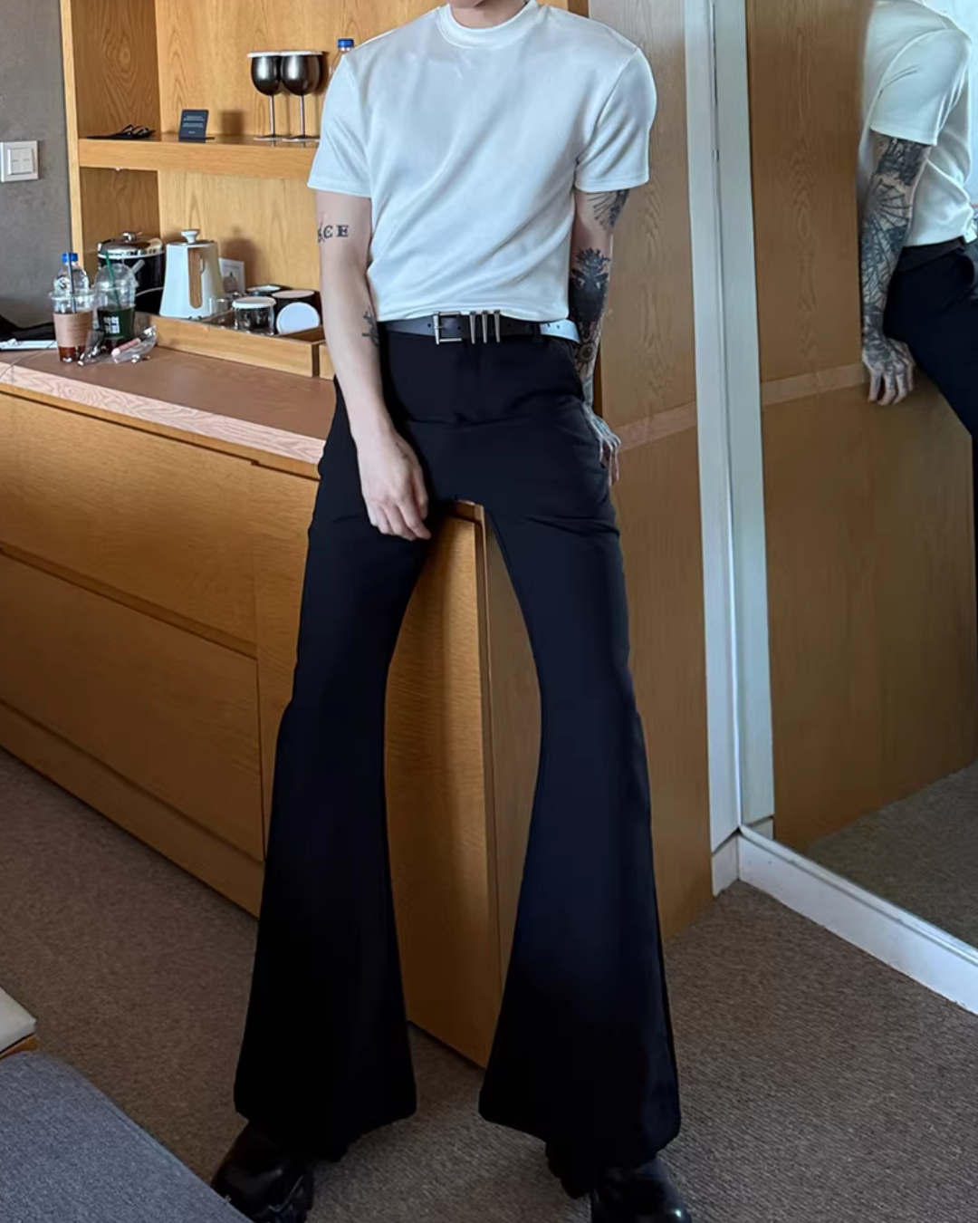 白色のクルーネック半袖カットソーと黒色のフレアパンツ。金属バックルのベルト付き。