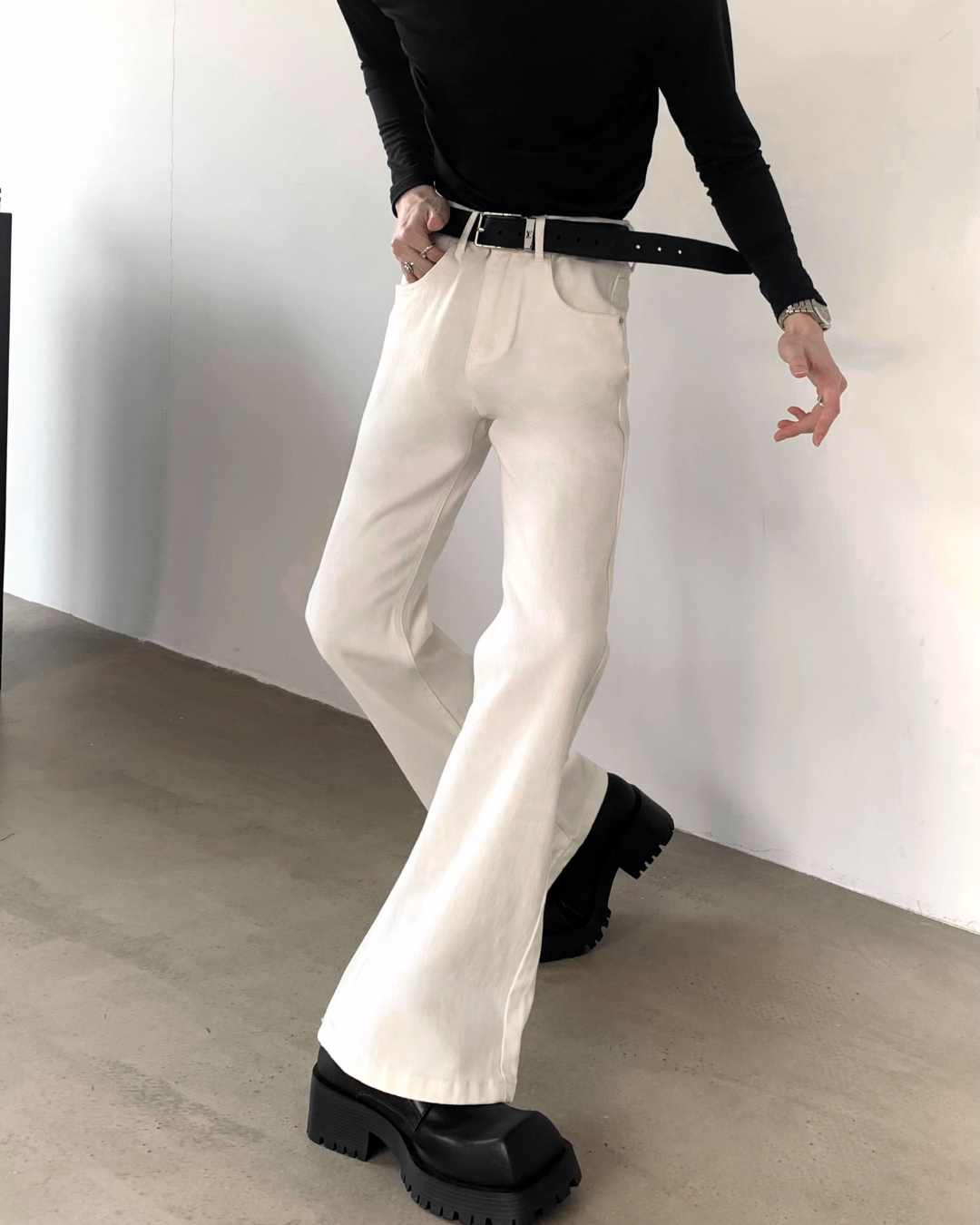 メンズのオフホワイトのハイウエストフレアデニムパンツ。黒レザーベルト付き。裾はフレアシルエット。