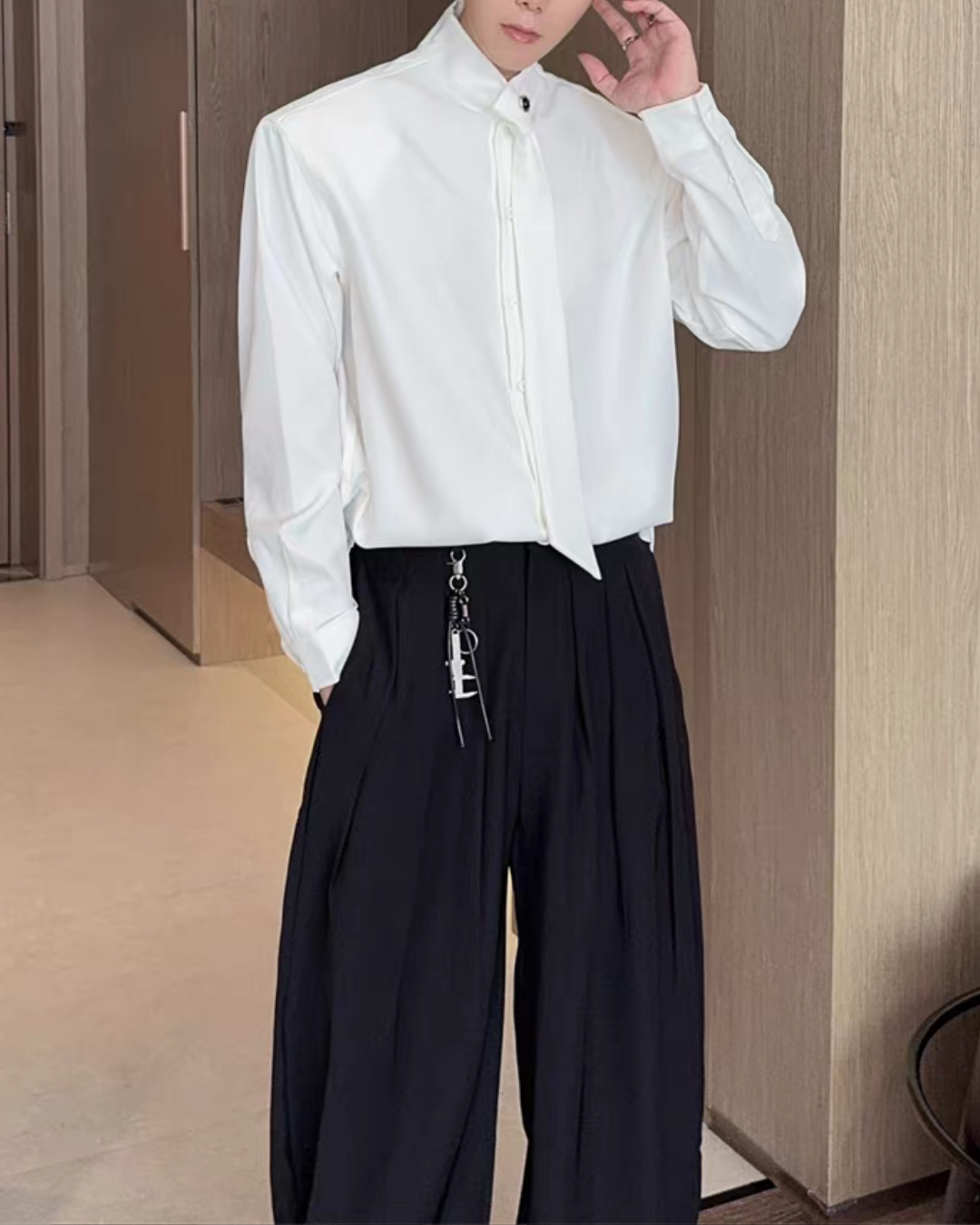 白色のシャツ。スタンドカラーと前開きジップ、長袖。黒色ワイドパンツと合わせたモノトーン着用例。