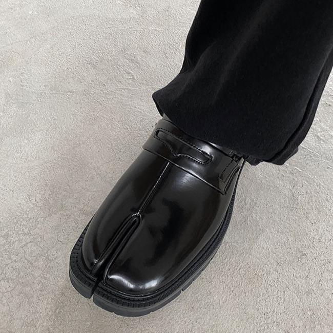 メンズの黒いエナメルレザーのタビデザインシューズ。つま先が二つに分かれた独特の形状で、甲部分にベルト留めのディテール付き。