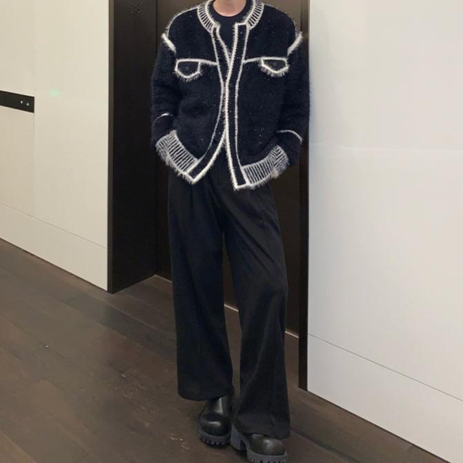 メンズの黒のモヘアタッチのカーディガンに黒のワイドパンツと厚底の黒い靴を合わせた全身の着用姿。白の縁取りと縞柄リブが目立つ。