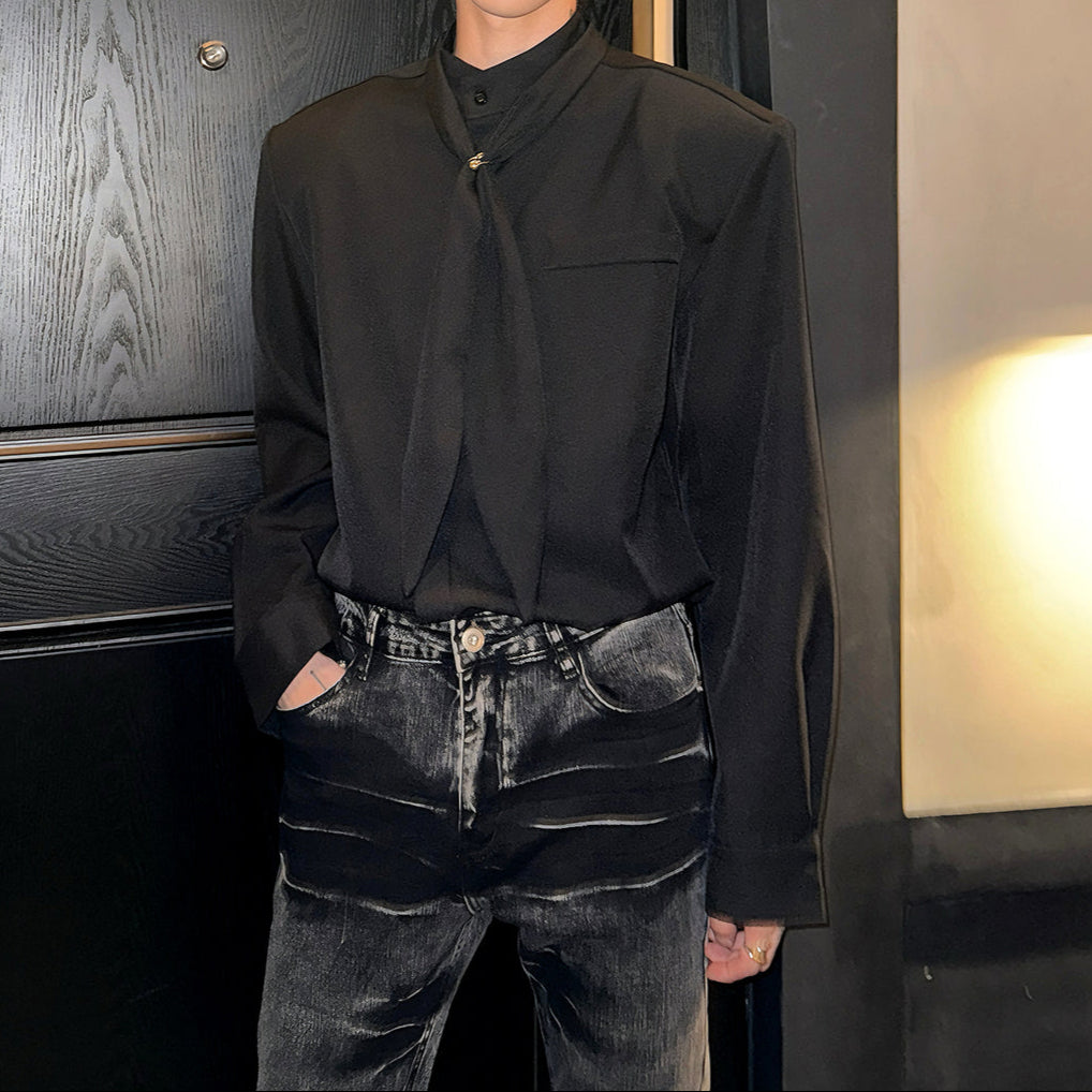 黒いシャツ。スタンドカラー、前立てに金具ボタン、胸ポケット付き。長袖でドロップショルダーシルエット。濃紺デニムと合わせた着用イメージ。