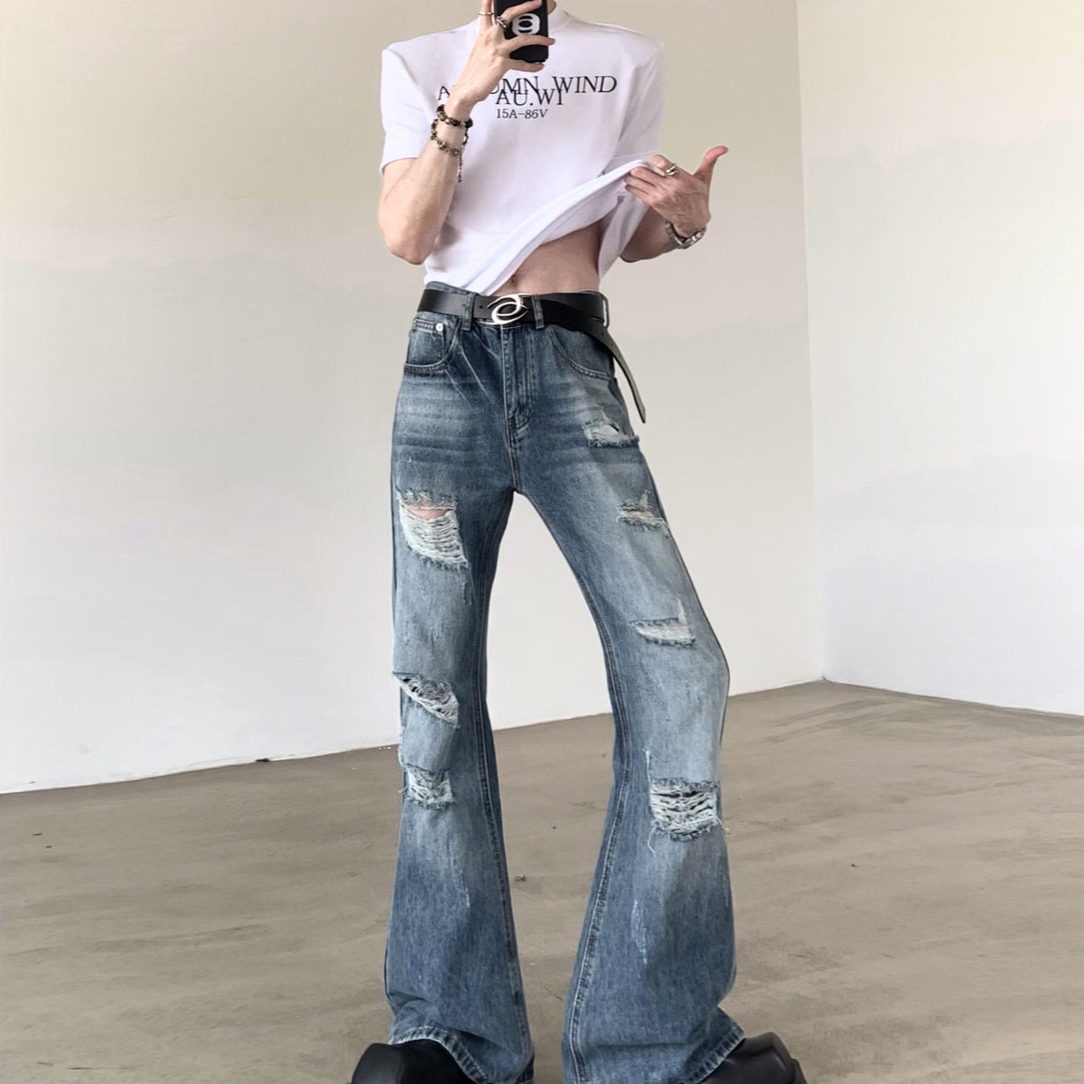 白地にロゴプリント入りのTシャツ。ルーズなシルエットで、短丈からハイウエストデニムとの合わせ想定。黒ベルト着用。