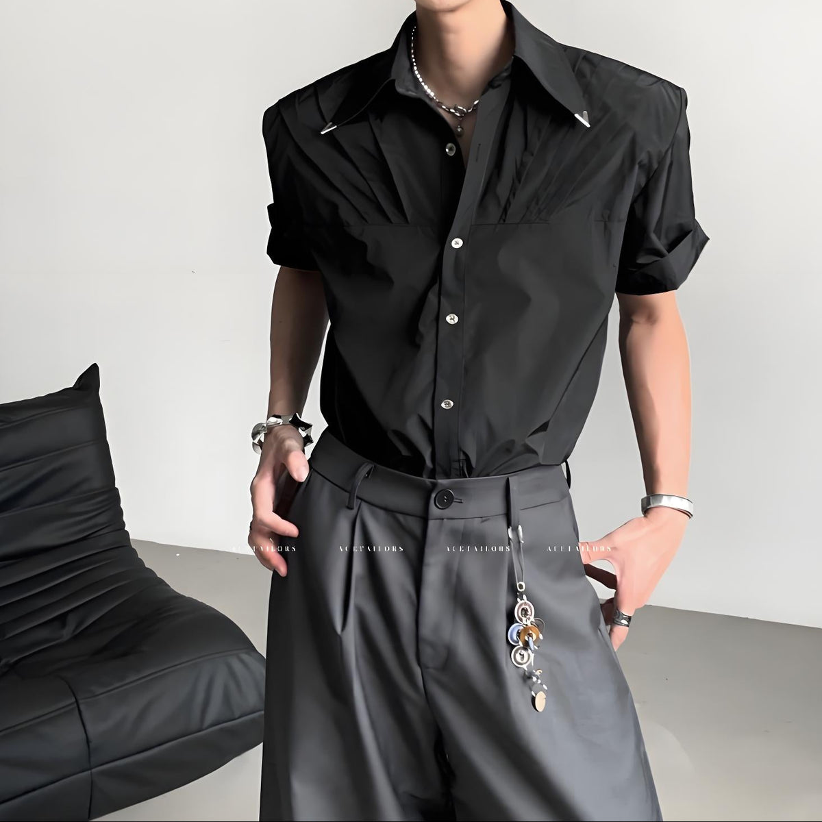 黒の半袖シャツ。襟に白いパイピング、白いボタンで前開き。オーバーサイズのシルエットにドレープ感がある。