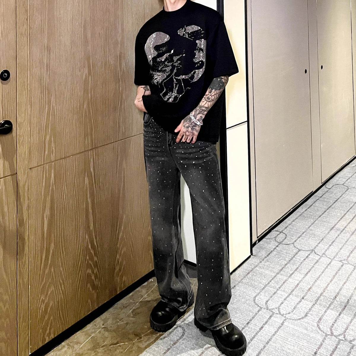 メンズの黒デニムパンツ。ウォッシュ加工と全体にクリスタル装飾が施された直筒シルエット。
