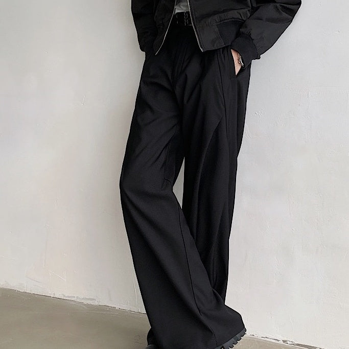 黒のワイドパンツ。ハイウエストで脇にタック入り、ドレープが縦に流れるシルエット。フロントポケット付き。