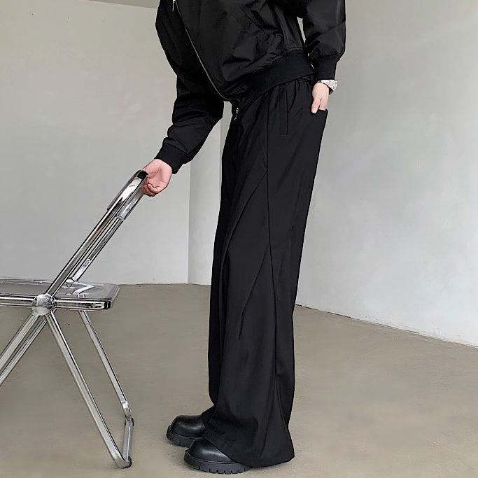 黒のドレープパンツ。ハイウエスト、ウエストゴム仕様で、脚部に深いドレープが入り、裾は広がるワイドシルエット。
