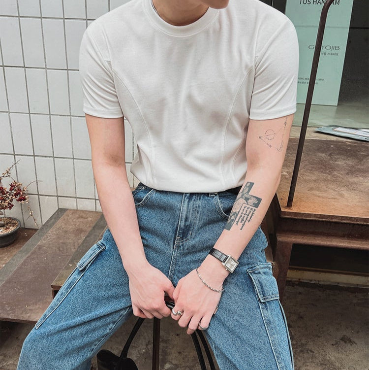白いクルーネック半袖Tシャツ。綿素材でリラックスシルエット、胸部にステッチディテール。