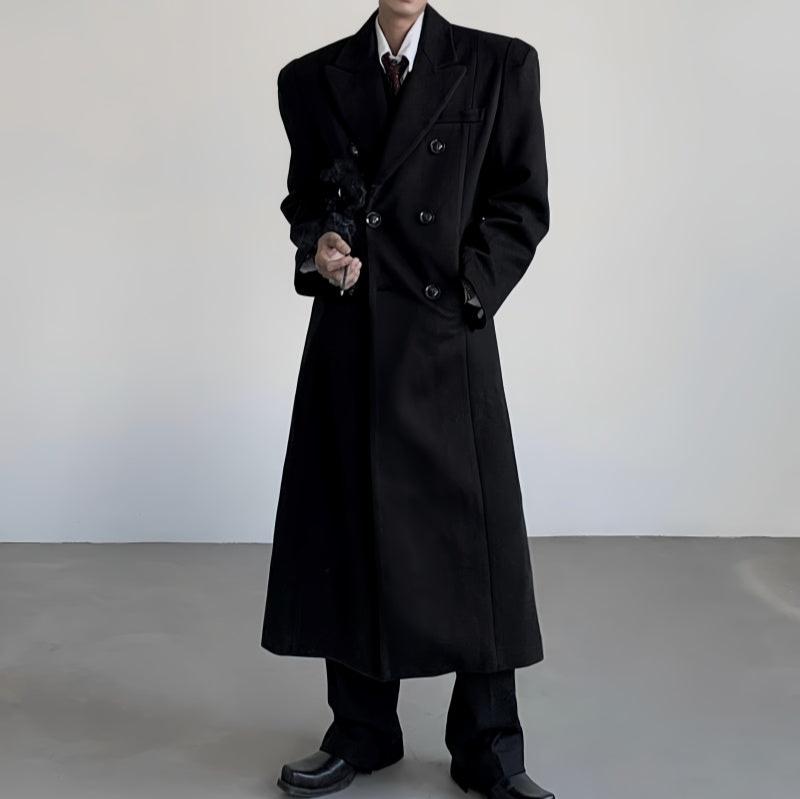 黒いダブルブレストロングコート。ウール素材で、ゆったりとしたシルエット、膝下までの着丈。ノッチ衿と玉縁ポケット付き。