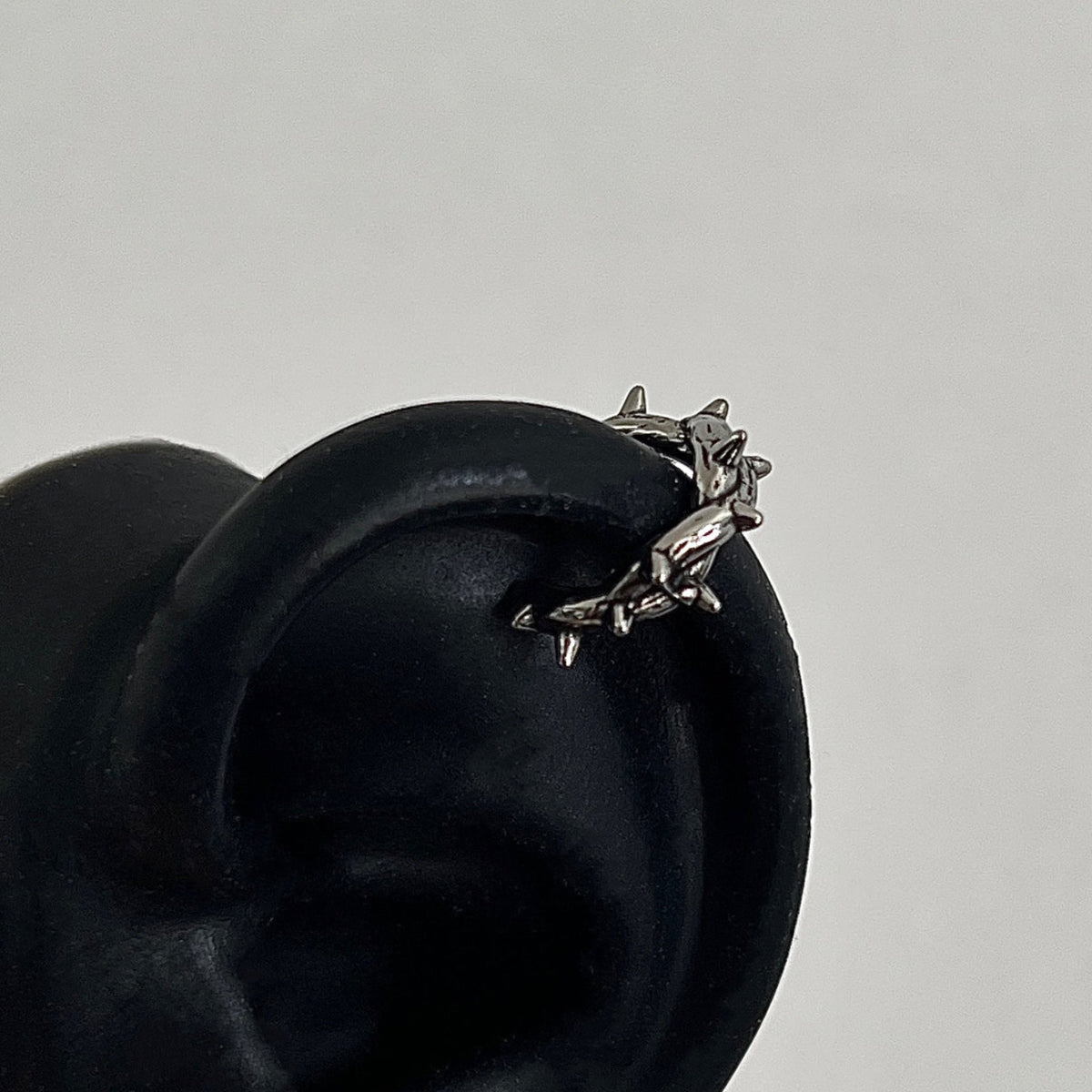 シルバー色の牛モチーフピアス。立体的な牛の頭部をかたどった金属製装飾が特徴。黒いベレー帽に装着された状態。
