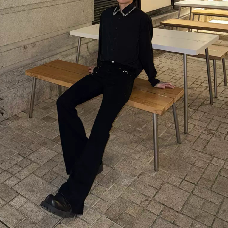 メンズの黒デニムのフレアパンツ。ウエスト周りにスタッズベルト装着。裾から膝上までフレアシルエット。