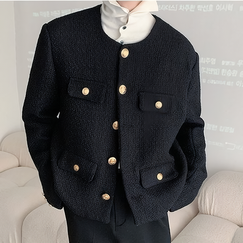 メンズの黒色のツイード素材ノーカラージャケット。ダブルブレストで金色のボタンが左右に配置され、深めのポケットが付く。ドロップショルダーのオーバーサイズシルエット。