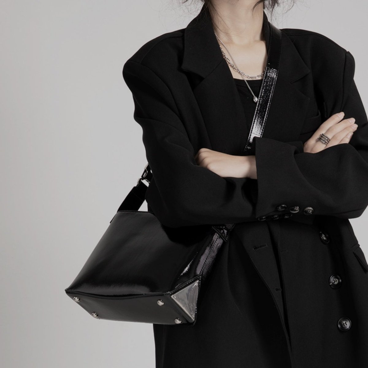 メンズの黒レザーのスクエアショルダーバッグ。金属バックルと三角形の金具、ショルダーストラップ付き。