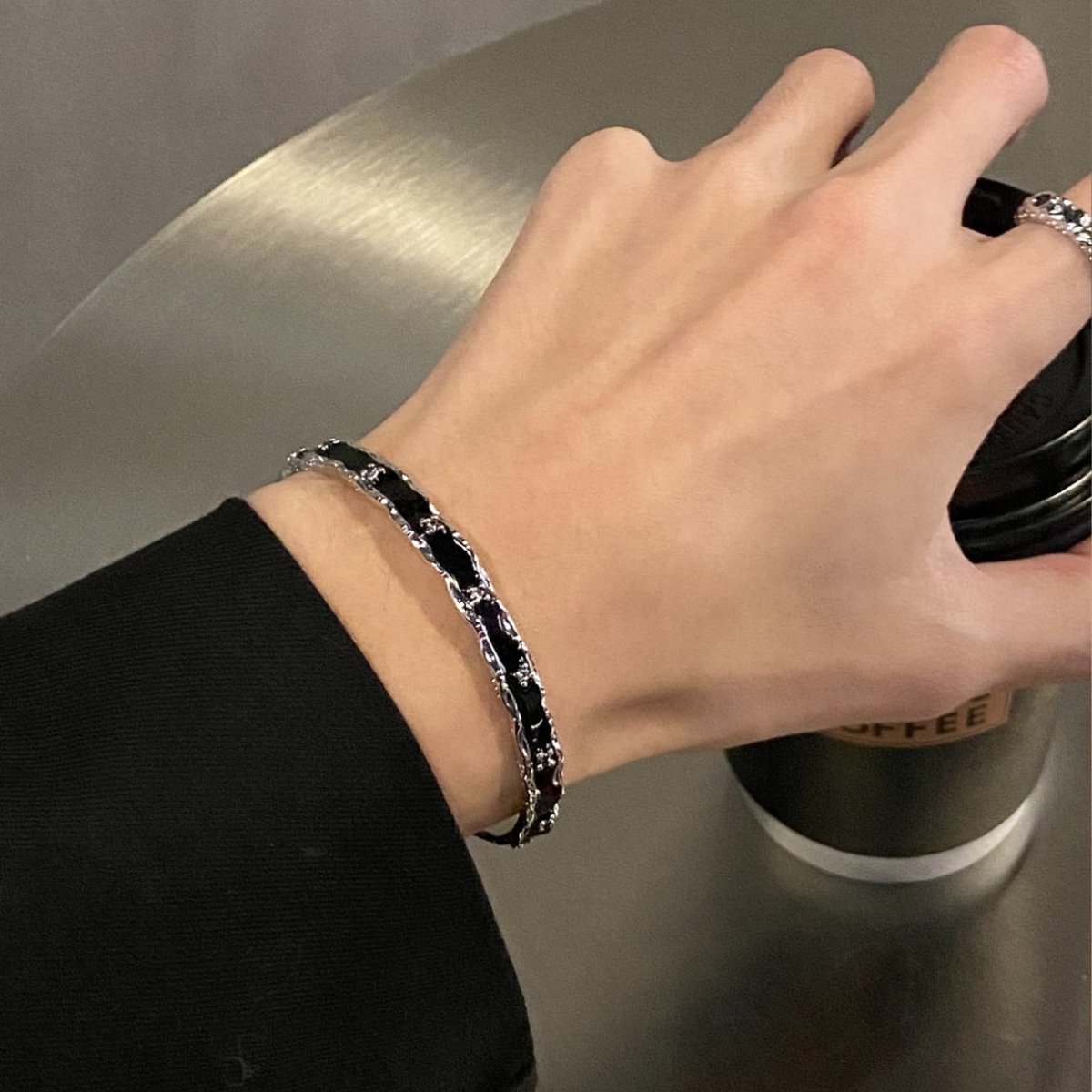黒とシルバーのリンクチェーンを組み合わせたバングル。手首に装着した状態で、光沢のある金属製チェーンと黒いエナメルコーティングされたリンクが交互に並ぶ。