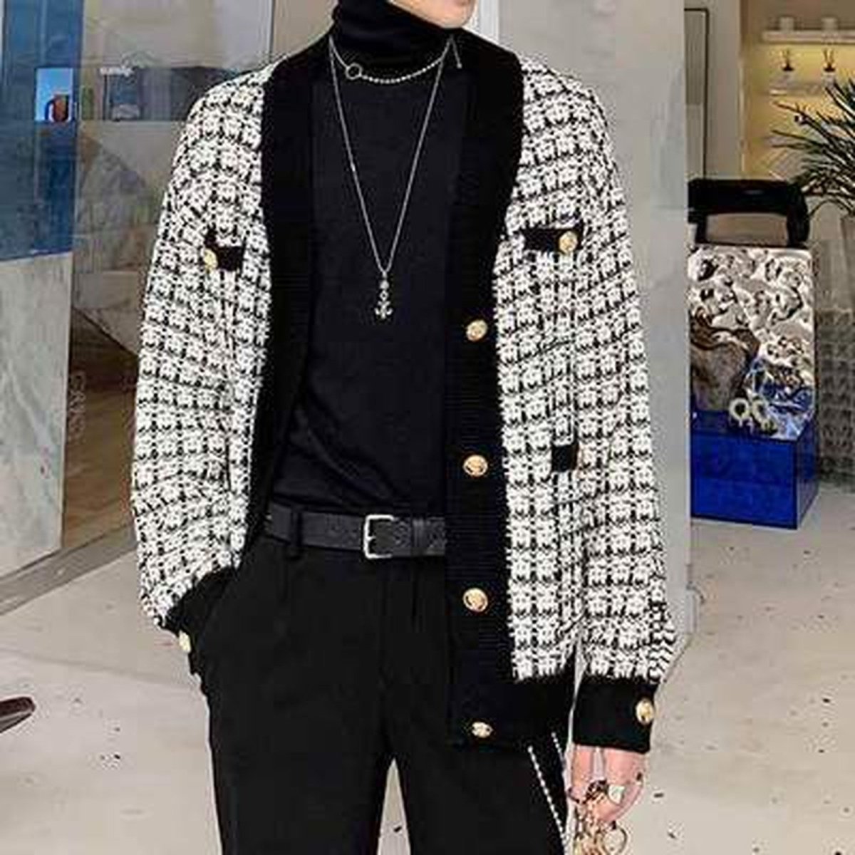 白黒ツイード素材のオーバーサイズジャケット。金ボタン付き、厚手のざっくりした質感で長めの着丈。黒いタートルネックとベルト付きパンツでコーディネート。