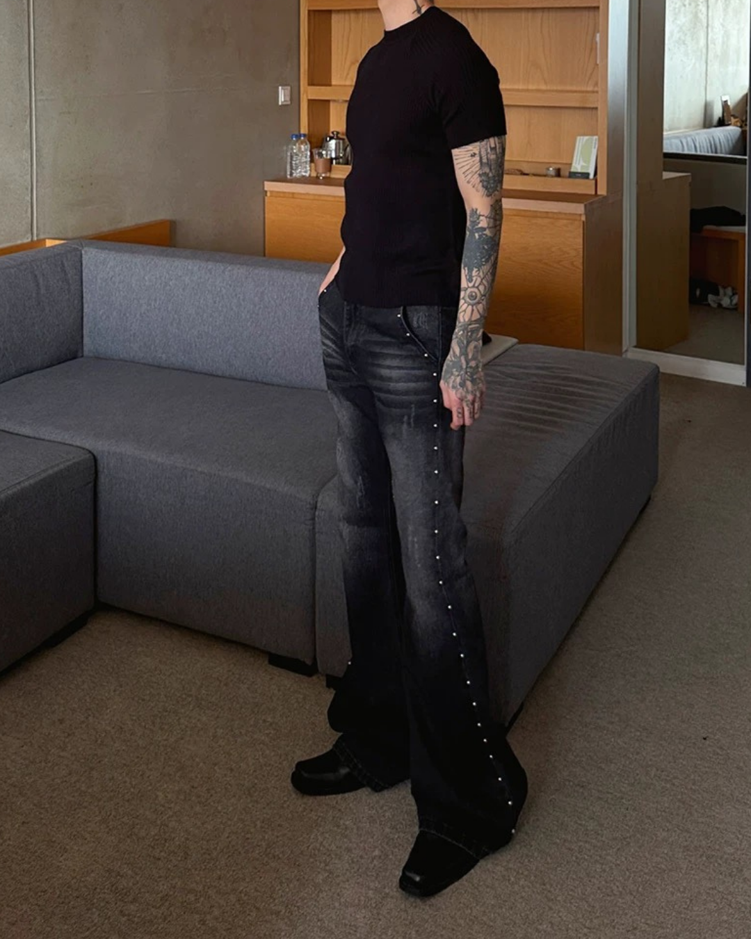 黒半袖Tシャツ。クルーネック、タイトシルエット。黒デニムパンツ、腰から裾にかけてスタッズ装飾。