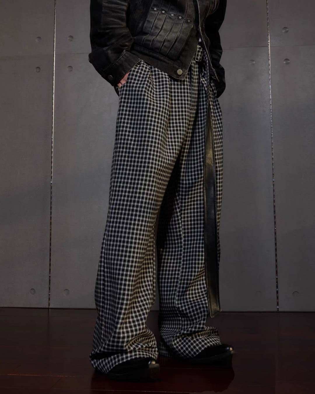 メンズの黒と白のギンガムチェックのワイドパンツ。タック入りで裾にたまる長さ、黒レザーの長いベルトを垂らし、デニムジャケットを合わせる