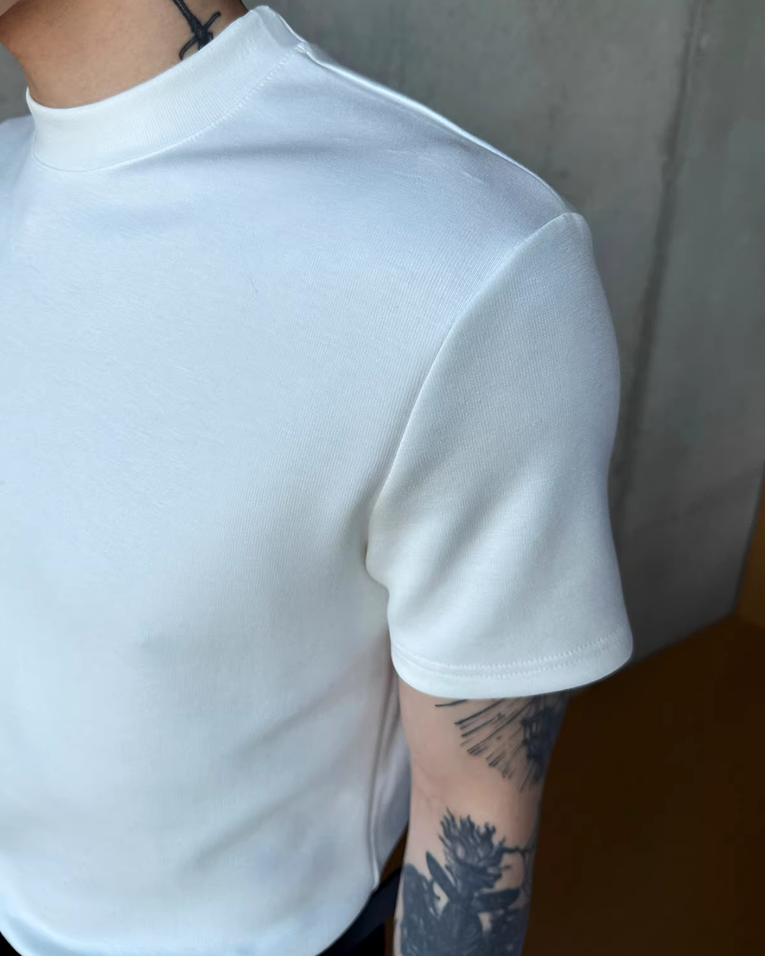 白い半袖Tシャツ。リブ編みのハイネック襟と厚みのある綿素材。スタンダードなドロップショルダーシルエット。