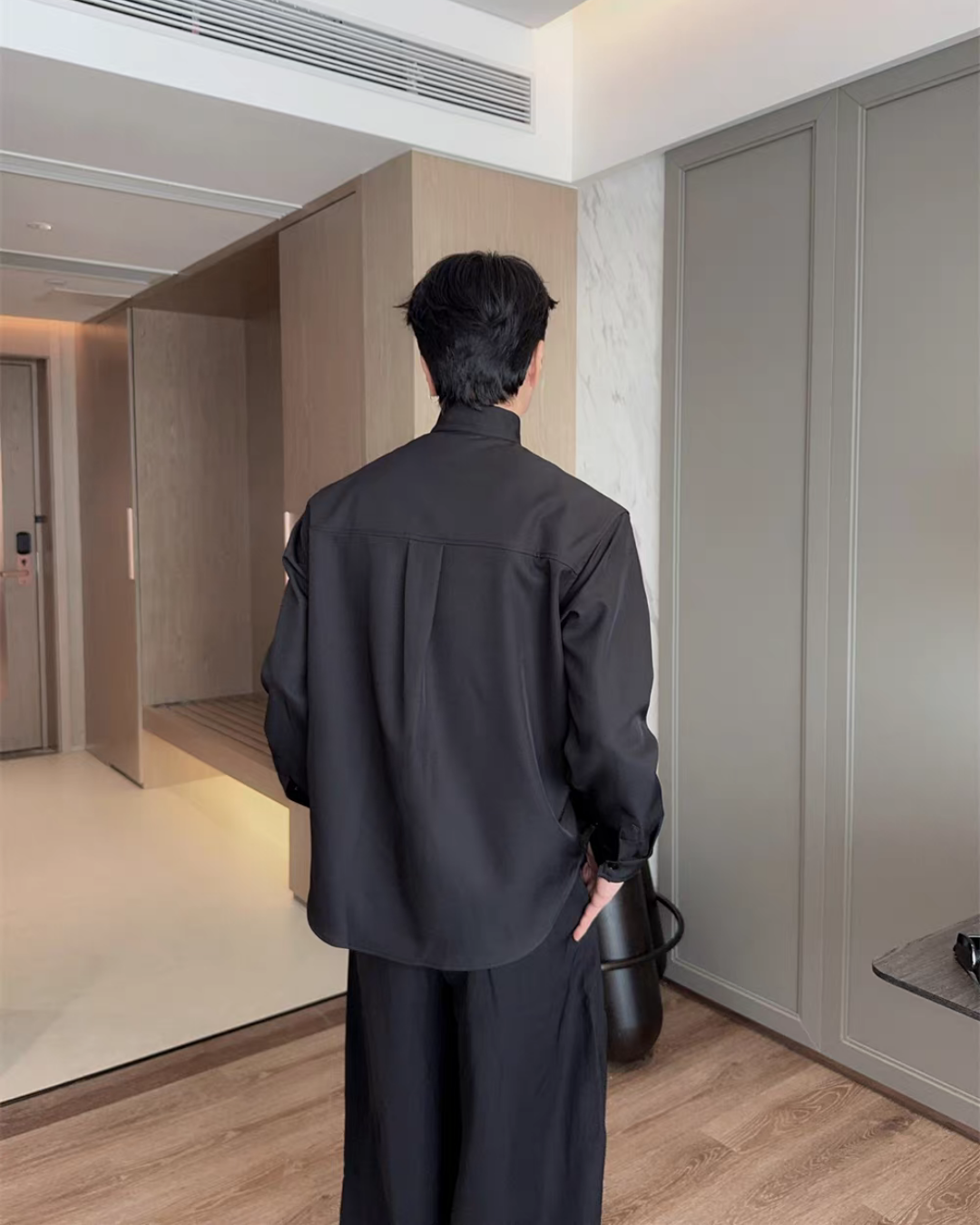 黒いシャツ。スタンドカラー、長袖、背中にタック入り、ドロップショルダーのやや大きめシルエット。