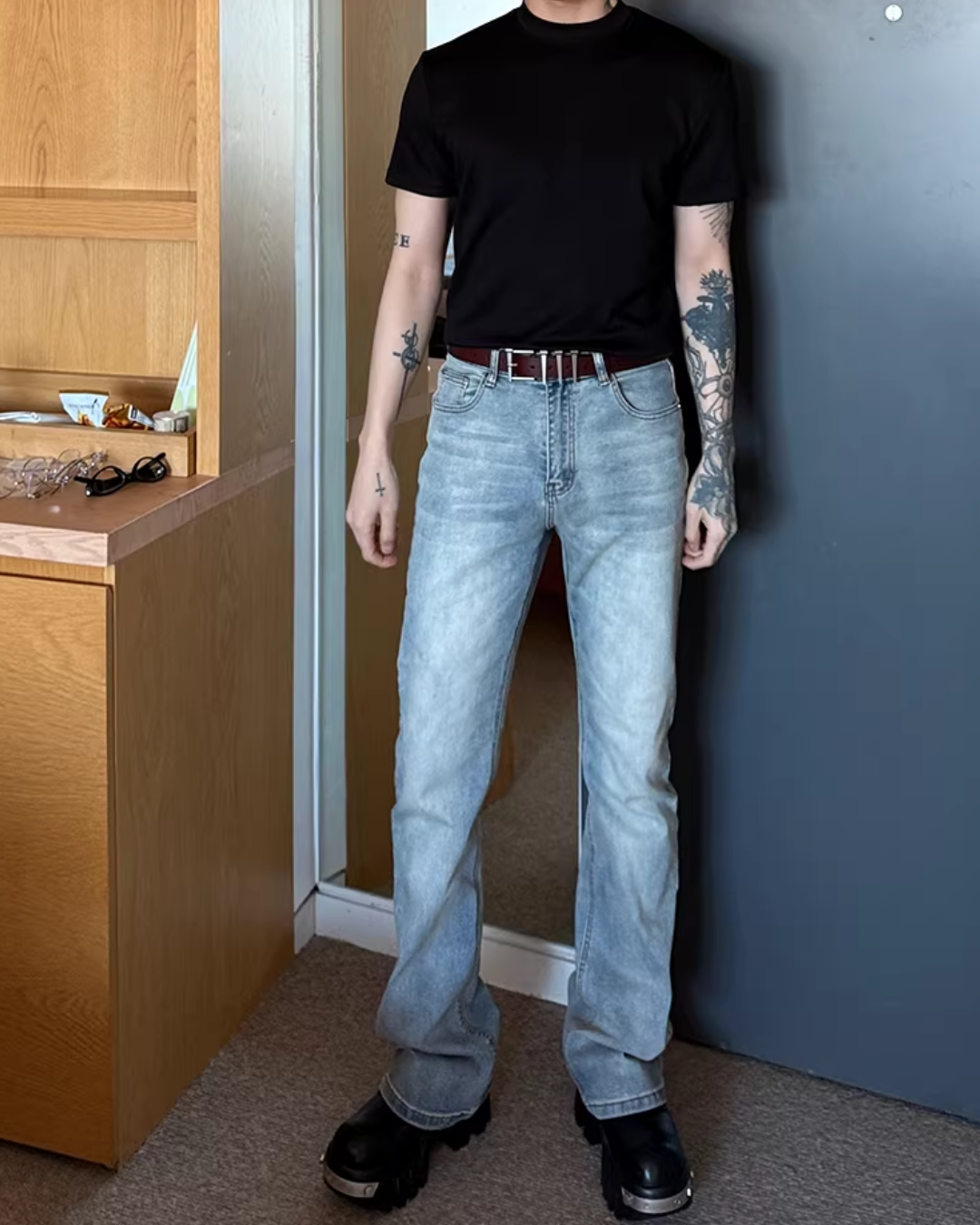 黒い半袖Tシャツ。クルーネック、シンプルなシルエット。浅めのインディゴブルーデニムパンツとベルト合わせ。