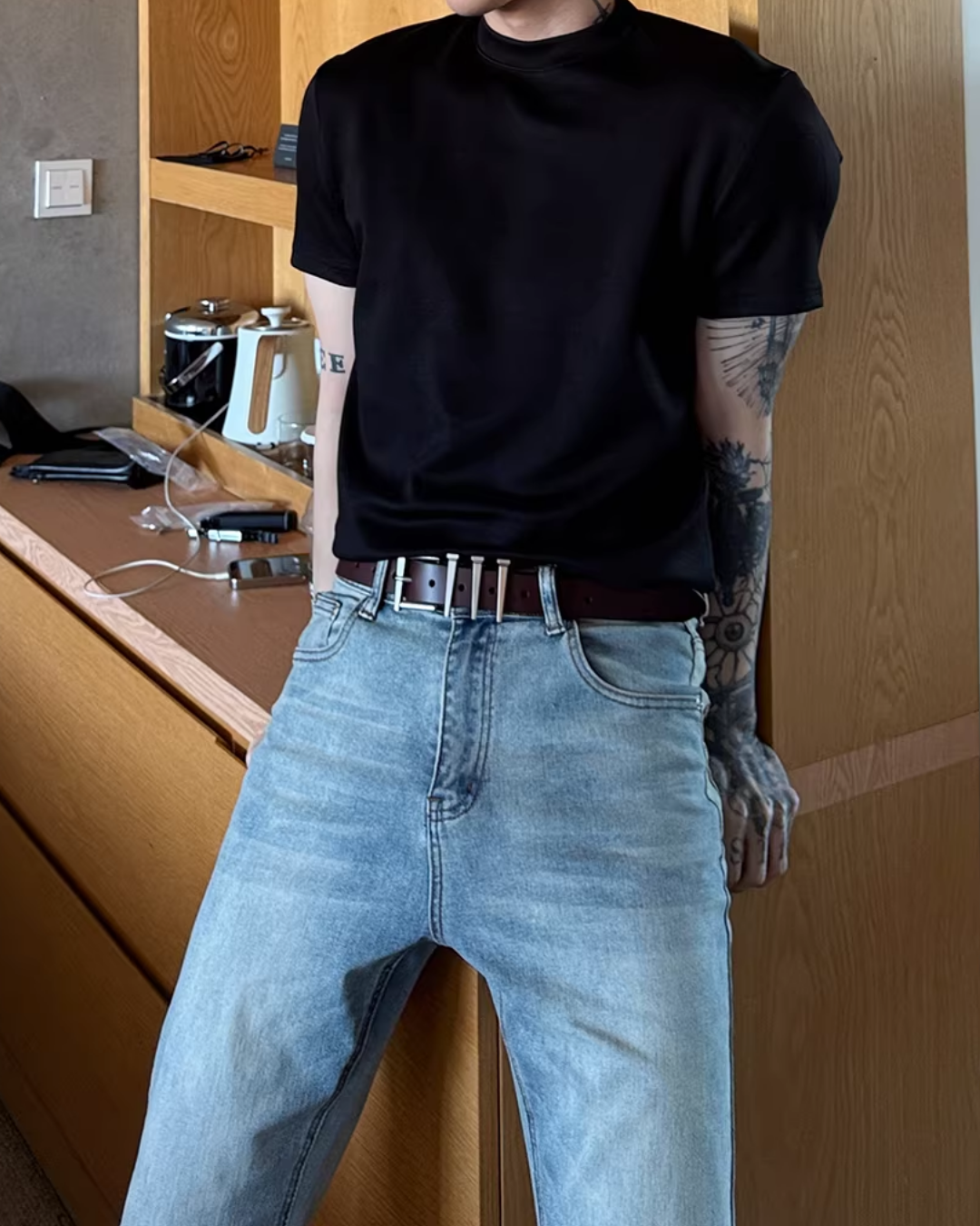 黒いクルーネック半袖カットソーと、ハイウエストの淡色デニムパンツ。白ベルト付き。