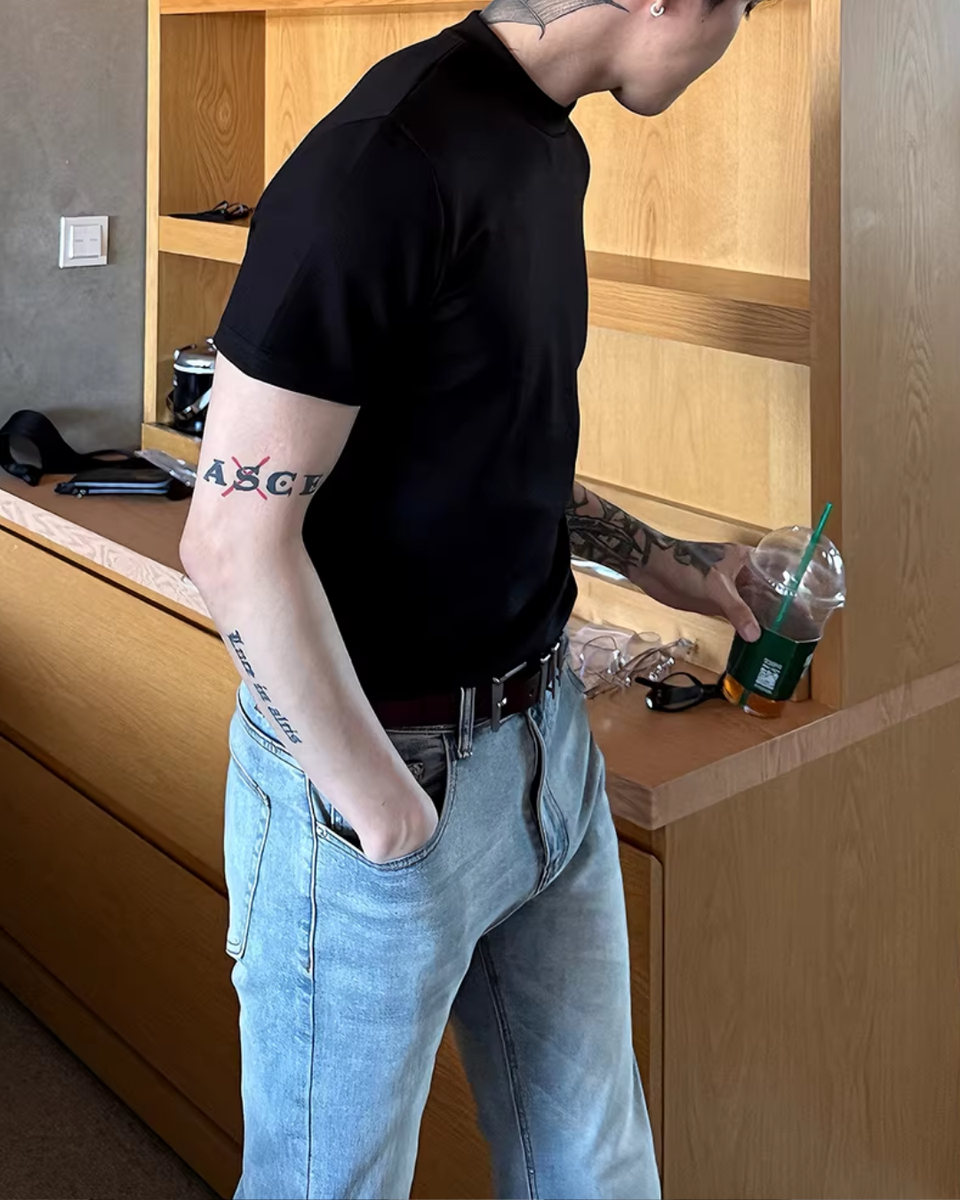 黒い半袖Tシャツ。スタンドカラーで、オーバーサイズシルエット。腕に英字ロゴプリント入り。