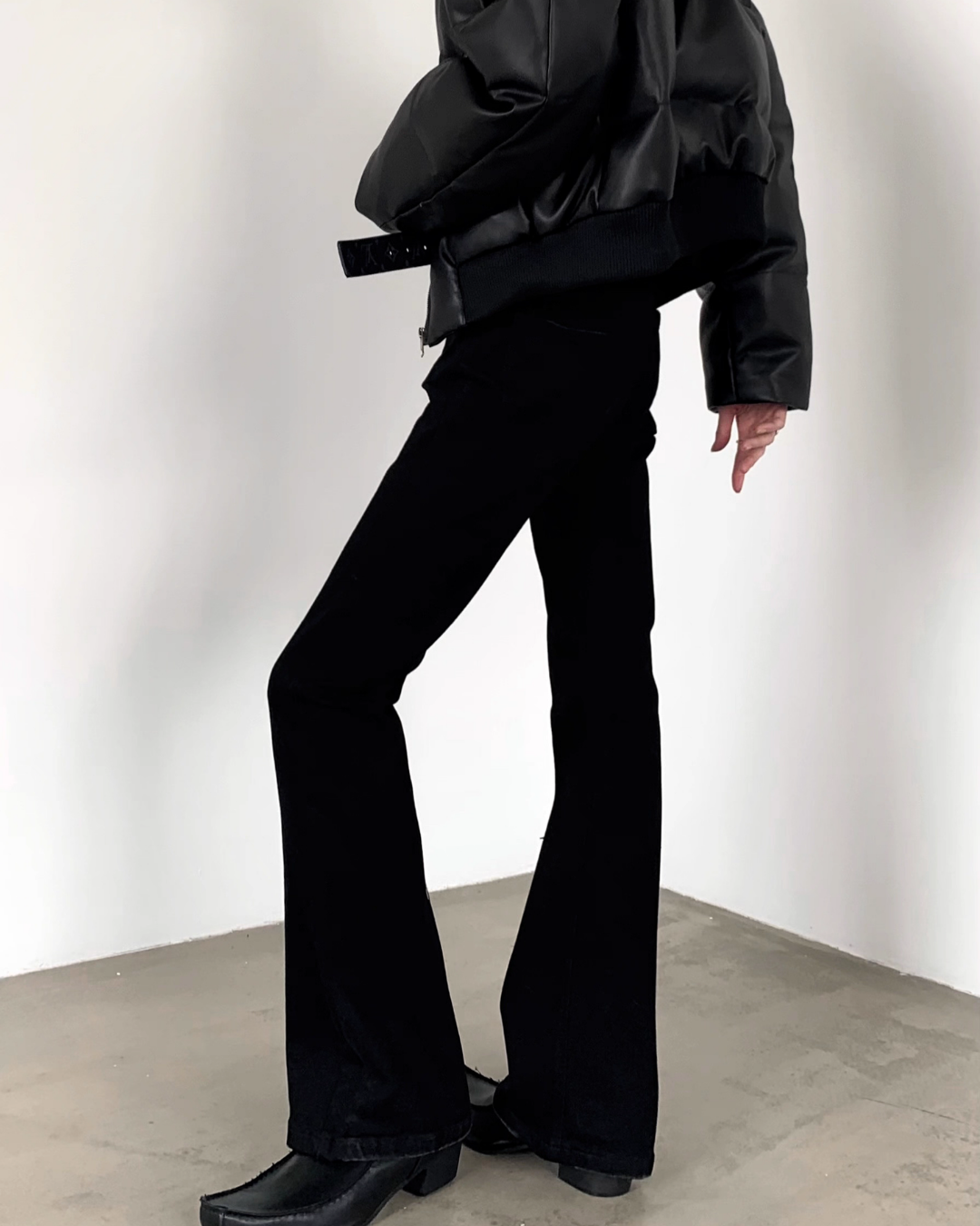 メンズの黒のハイウエストフレアデニムパンツ。太ももから裾にかけて広がるシルエット。黒ベルト付き。