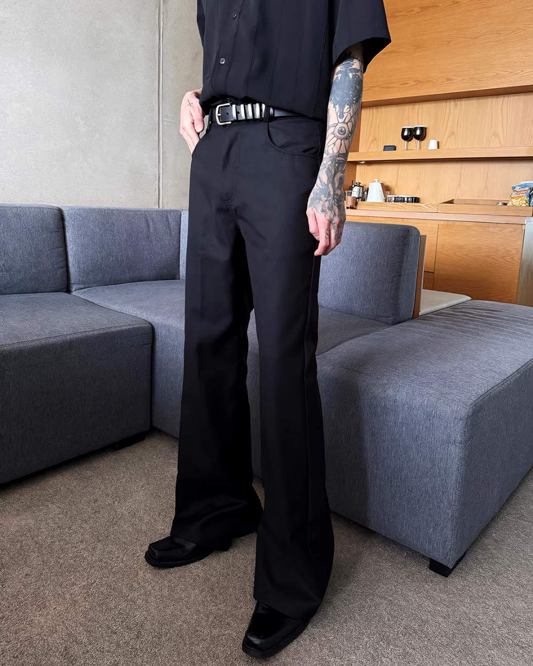 メンズの黒のストレートパンツ。ハイウエストで直線的なシルエット。白いバー金具のベルトを装着。