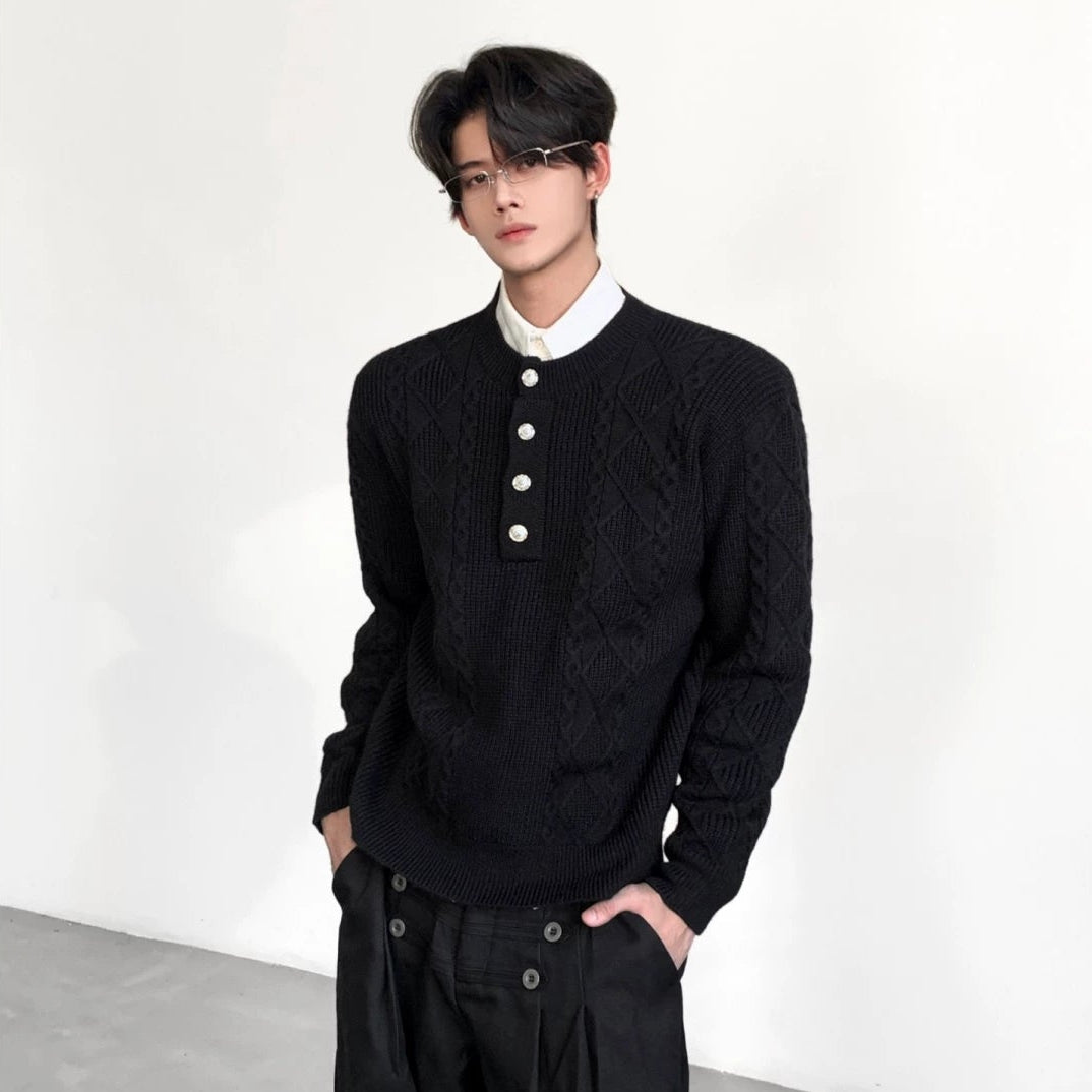 メンズの黒のヘンリーネックニット。白シャツの襟を重ね、黒のワイドパンツのポケットに手を入れた正面の上半身の着用写真。