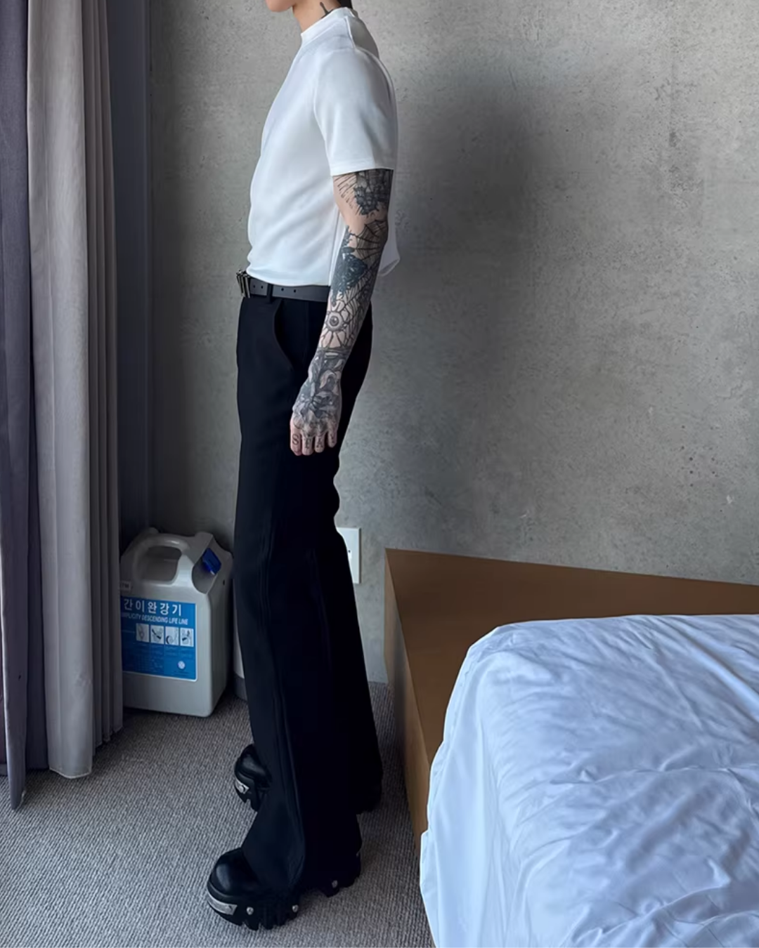 白い半袖Tシャツ。クルーネック、すっきりしたシルエット。黒いハイウエストパンツとベルト合わせ。