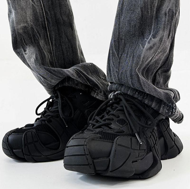 黒い厚底スニーカー。ラウンドトゥで立体的なソール構造、紐靴。グレーのデニムパンツを合わせた着用画像。