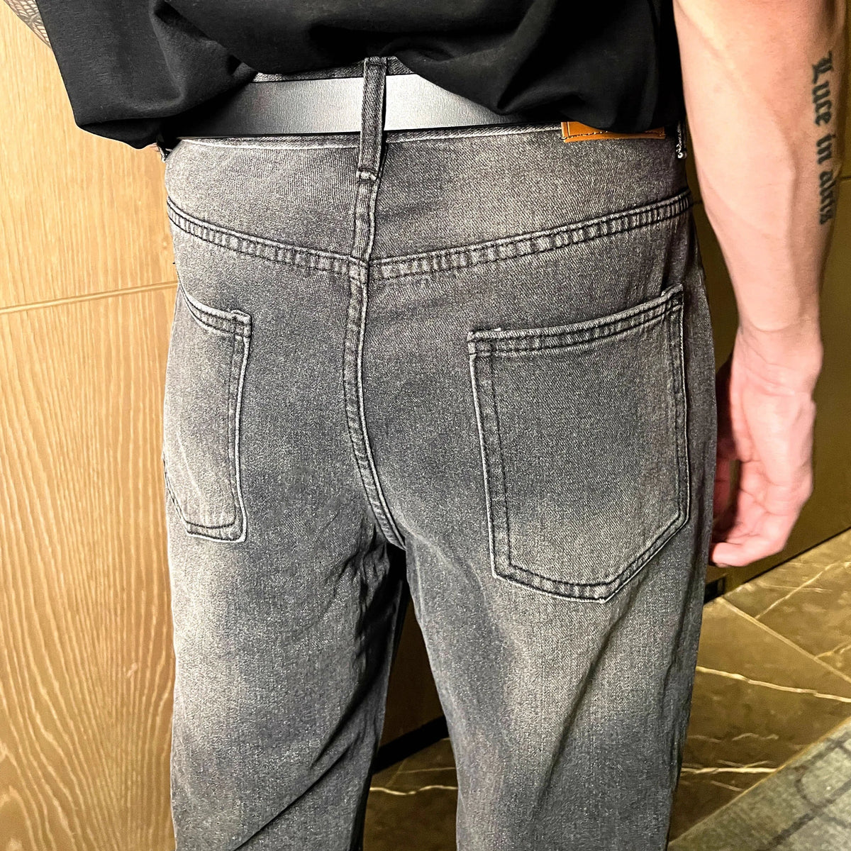 メンズのグレーのクリスタルウォッシュ加工デニムパンツ。スタンダードな5ポケット仕様で、ハイウエストシルエット。背面は腰ポケットが配置された着用写真。