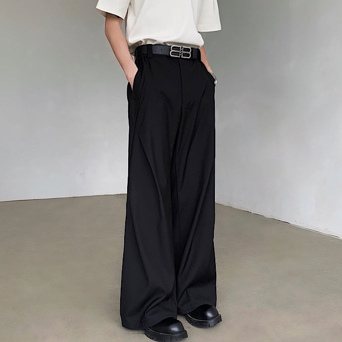黒のドレープパンツ。ハイウエスト、ワイドシルエット。金具付きベルト、両脇ポケット、着丈は足首まで。