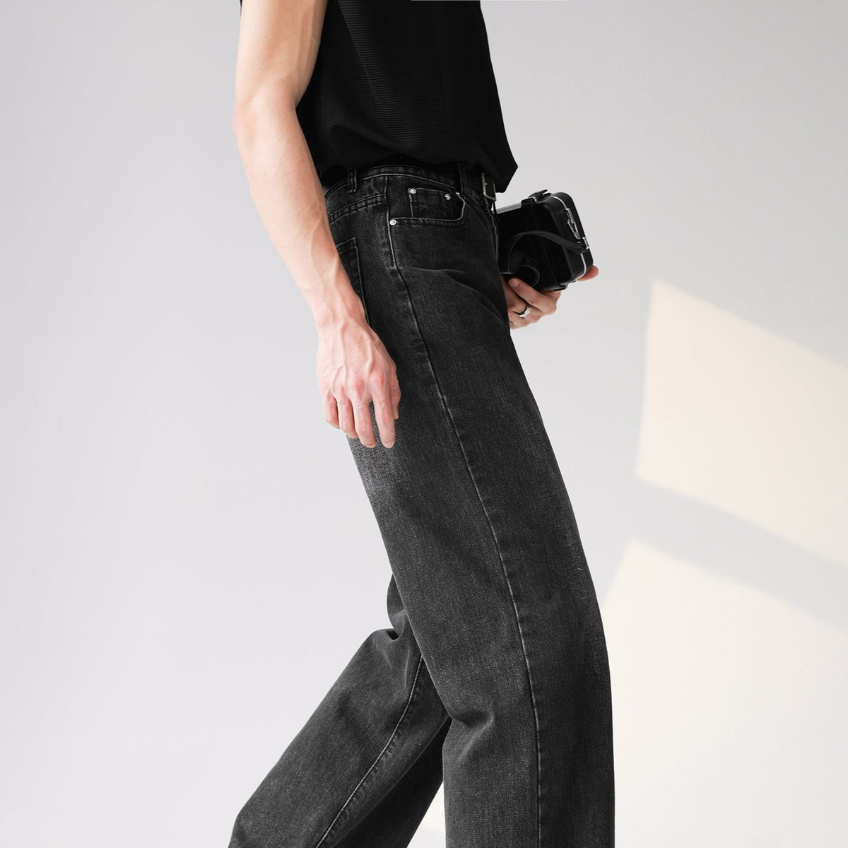 メンズの濃いグレー色のデニムパンツ。センターシームが施された立体的なシルエットで、ハイウエスト仕様。足首に向かってフレアに広がるストレートシルエット。