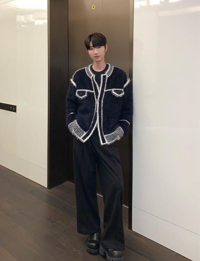メンズの黒のモヘアタッチのカーディガンを正面から写した全身の着用姿。白縁の胸ポケットと縞柄リブ、黒のタックパンツと厚底の靴。