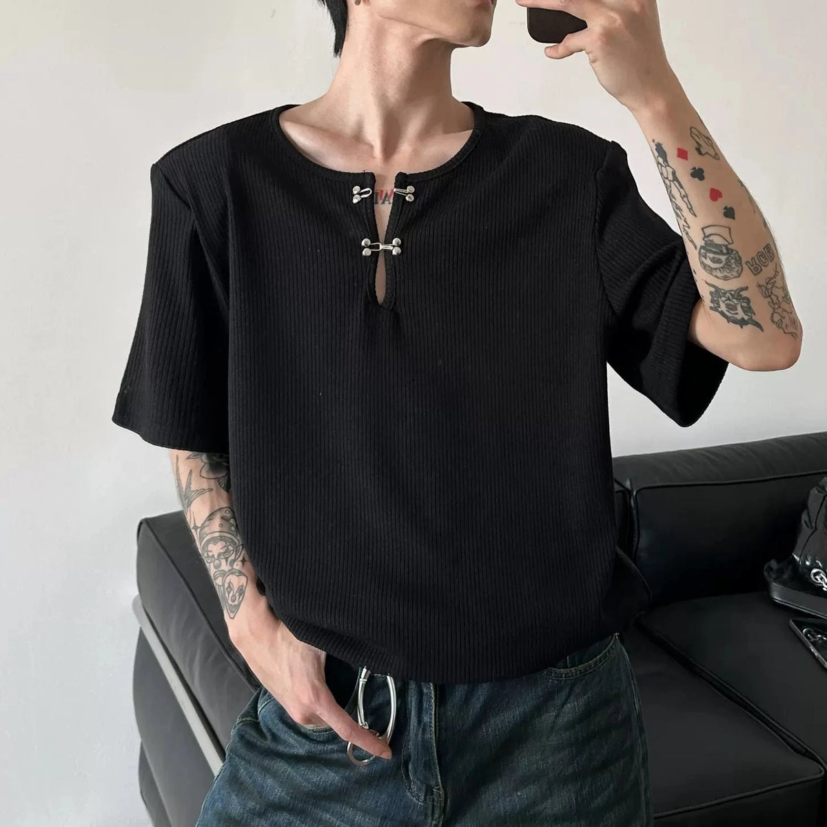 黒のリブ素材カットソー。クルーネック、半袖。胸元に金属製のホック留めとキーホール開き。