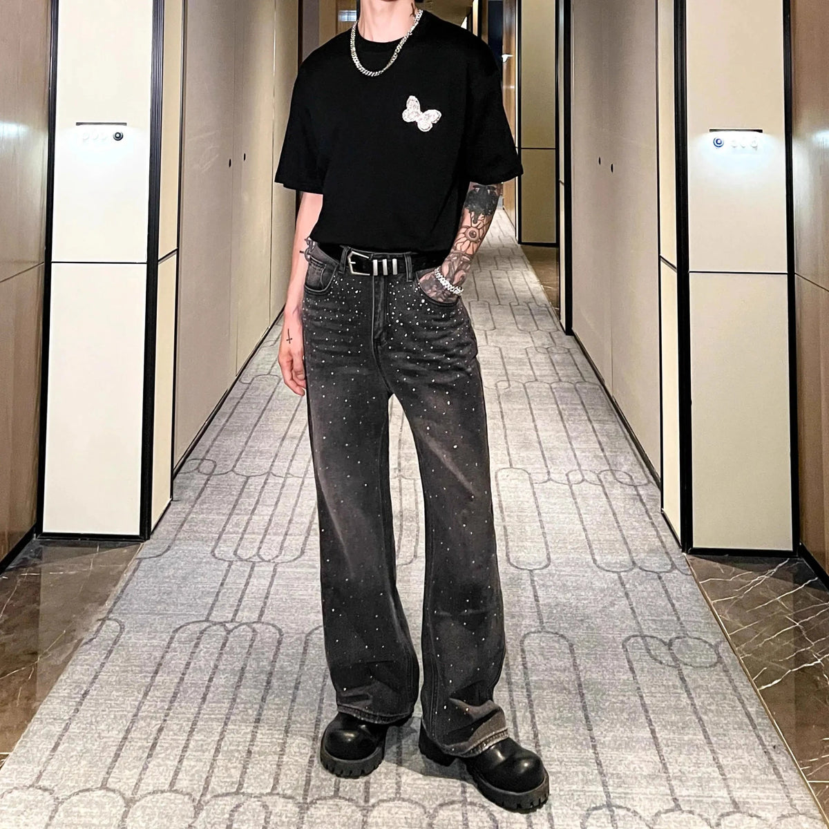 黒デニムパンツ。全体にクリスタル装飾があり、ハイウエスト・ストレートシルエット。メタルベルト付き。