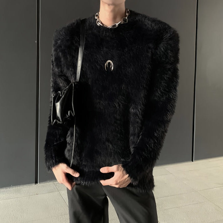メンズの黒のシャギーニットの胸元にシルバーの月形金具。肩にボリュームがあり、黒いレザーバッグを肩に掛けた着用。