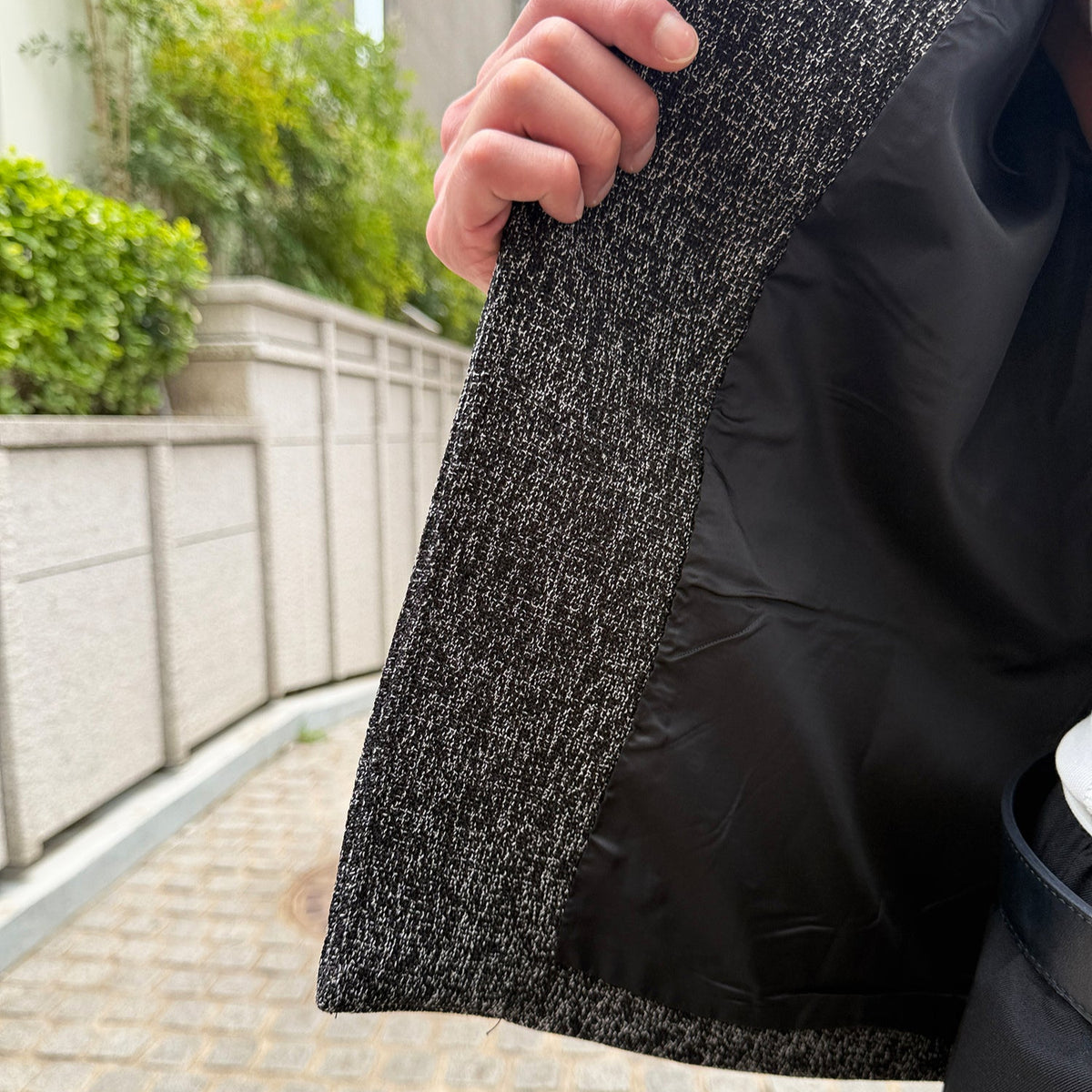 メンズのジャケットの前身頃を持ち上げた内側の画像。黒いツイード生地の裏側に、黒のライニング（裏地）が付く