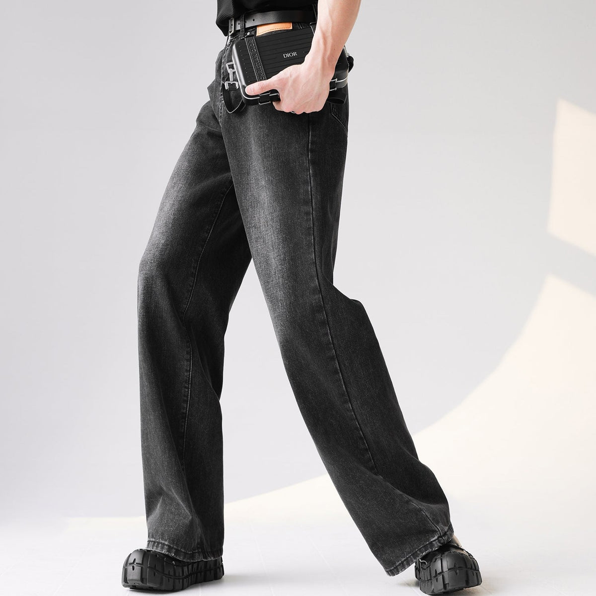 チャコールグレーのワイドデニムパンツ。直線的なシルエットで、裾は広がったワイドフレア。ウエストに黒レザーベルトを合わせた着用画像。